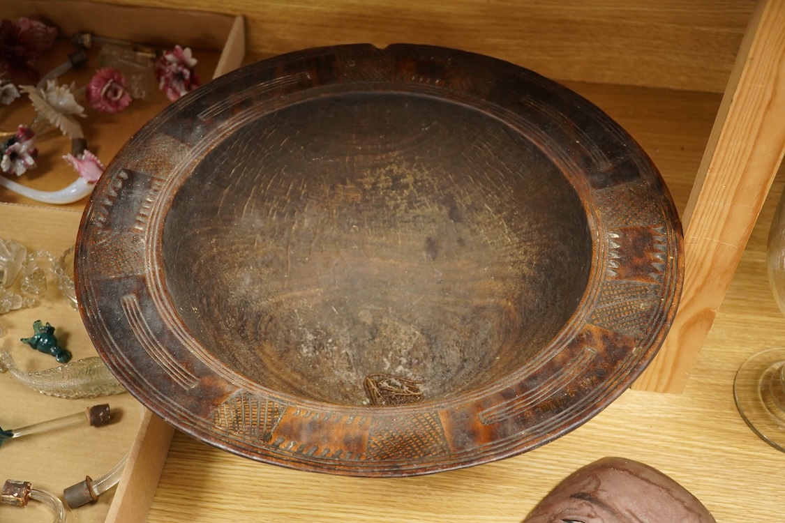 A wooden bowl with a decorative carved rim - 44cm wide across rim and an oriental carved and painted wooden face mask